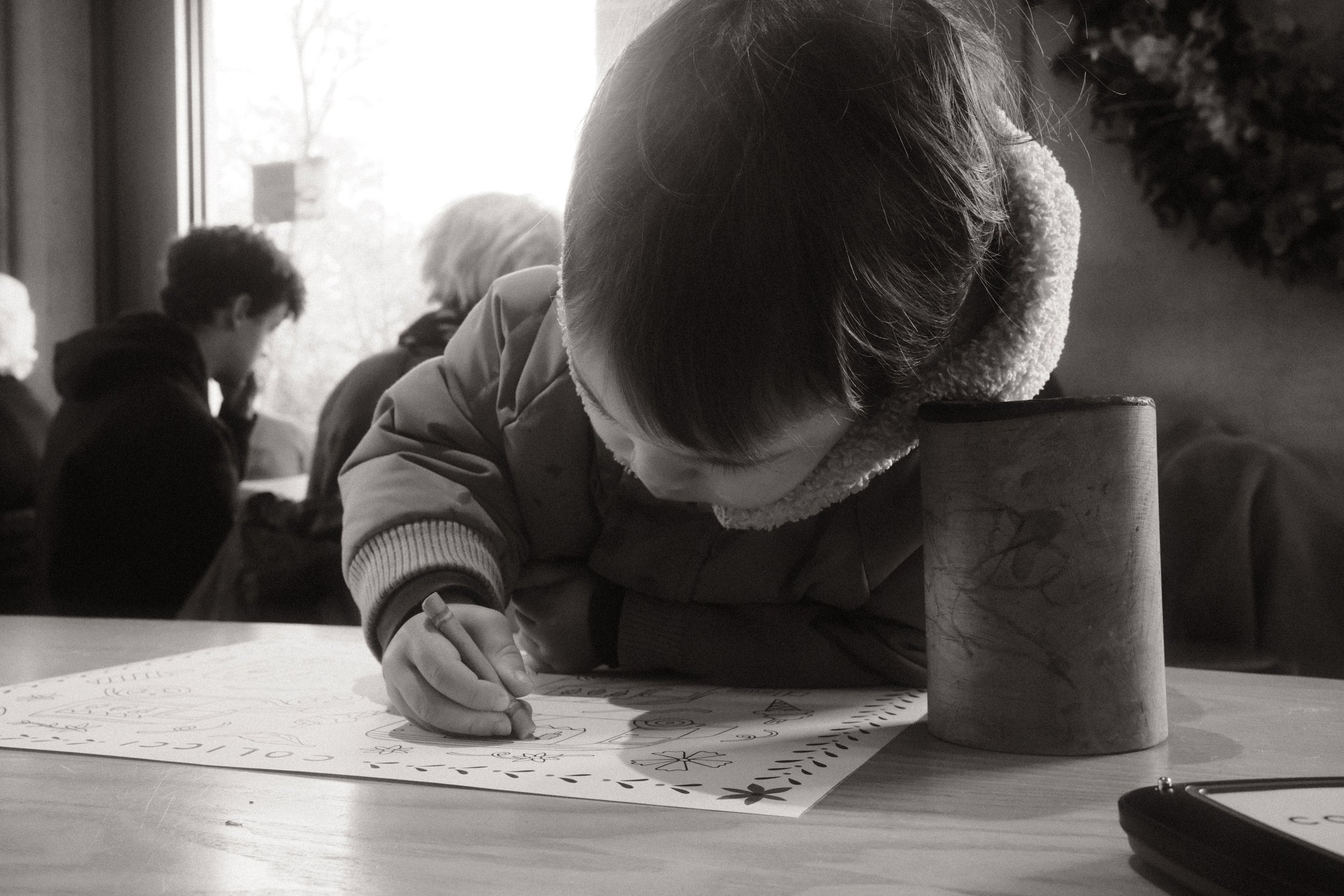 a young boy hunched over a piece of paper, a blunt crayon in one hand