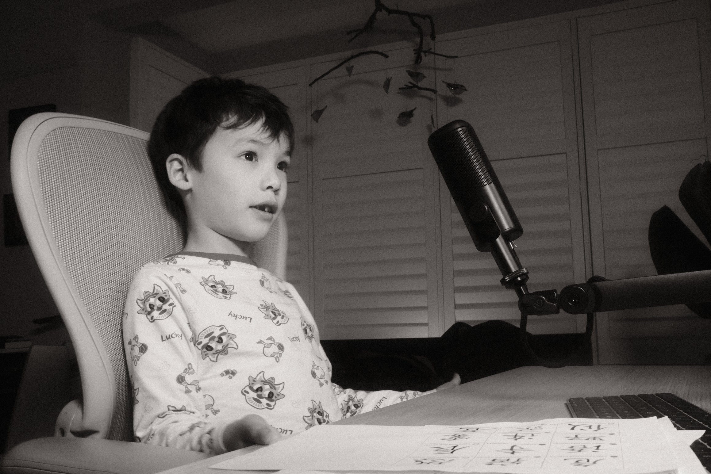 a black and white photo of a boy sitting at a desk in front of a microphone