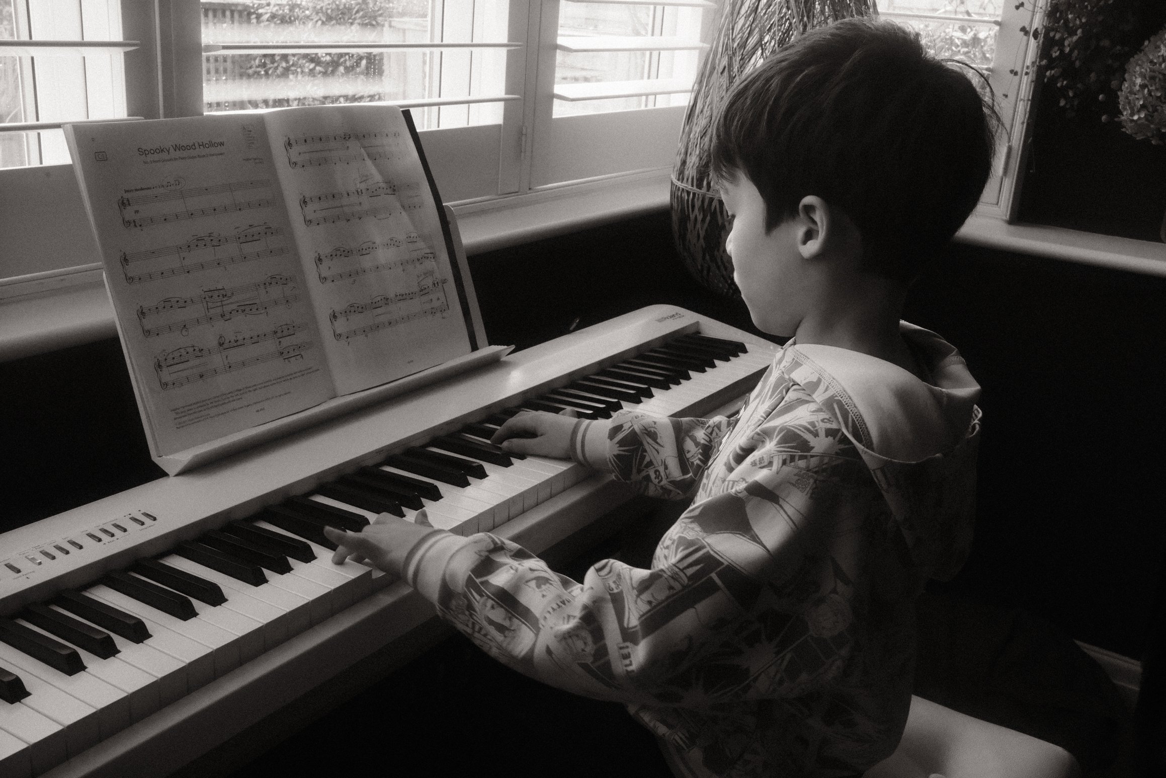 a black and white photo of a boy playing the piano