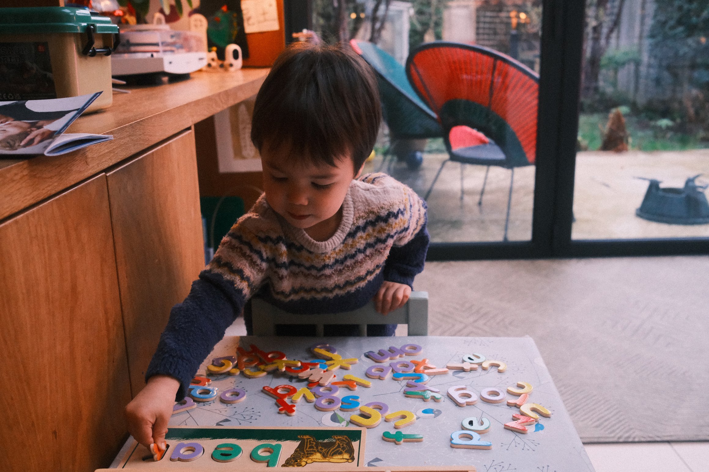 A young boy spells out the word 'bear' by placing letters onto a board.