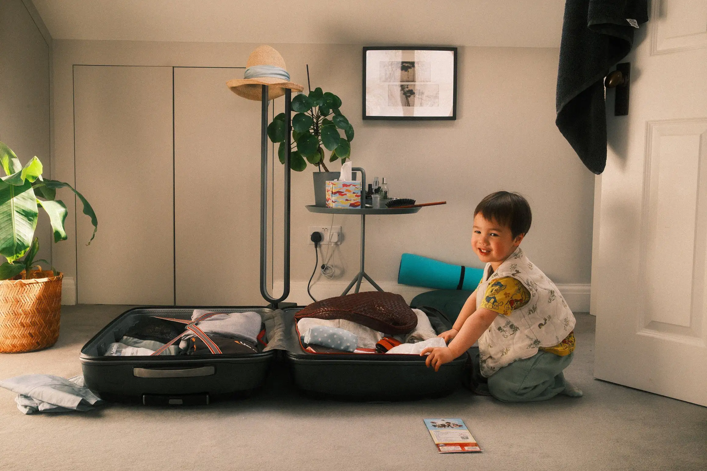 a young boy kneels beside a packed suitcase