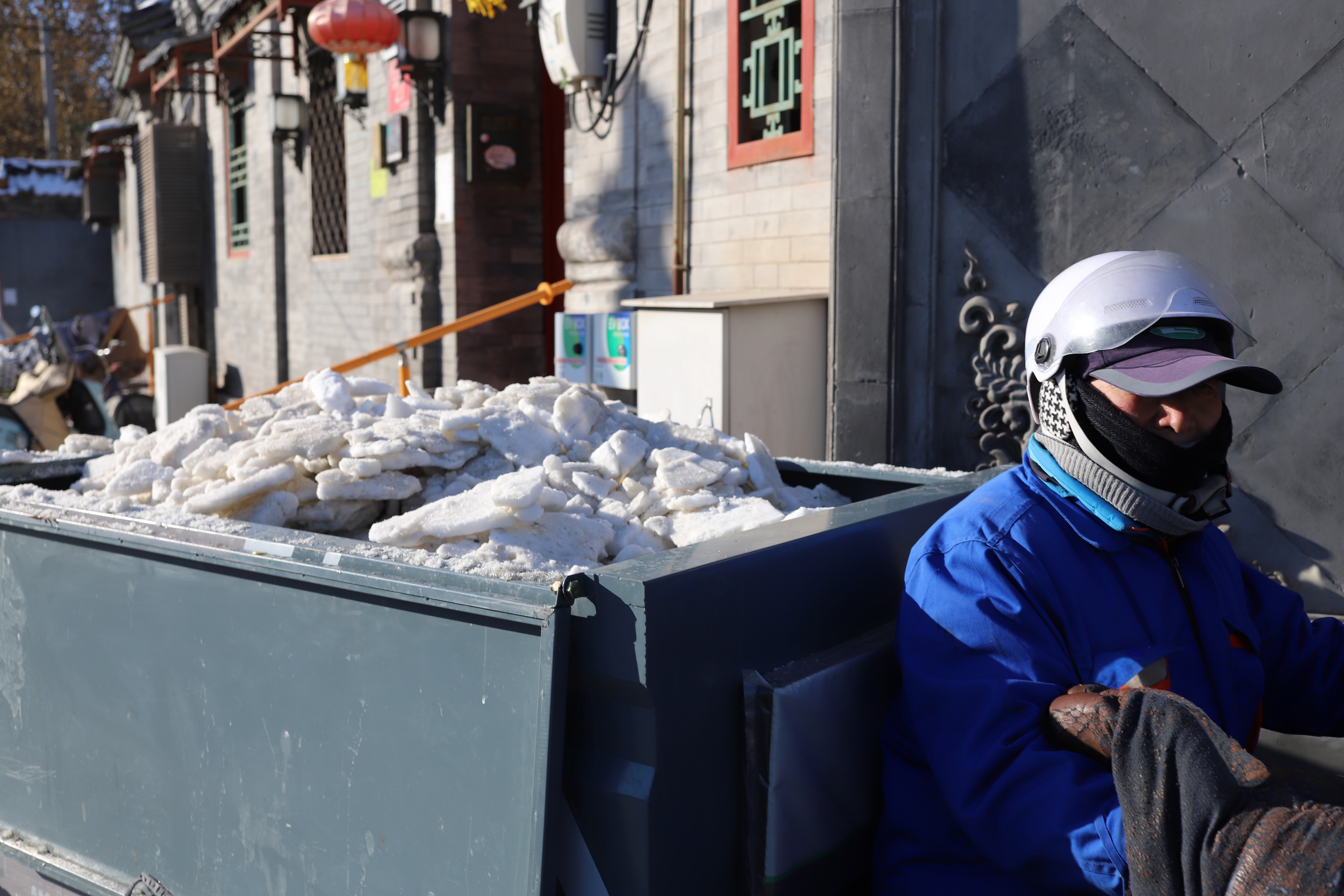 Sheets of snow being removed on the back of a tricycle.
